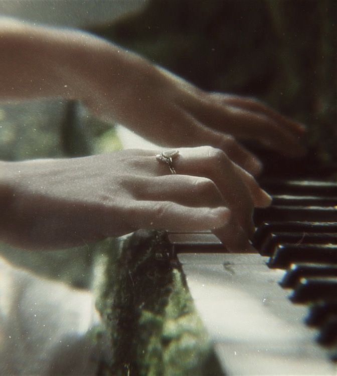 two hands are playing the piano with their wedding rings on top of it, while another hand rests on the keyboard