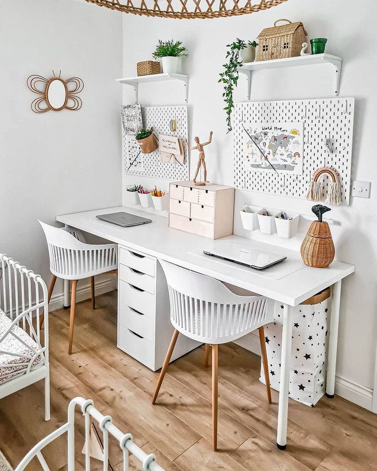 a white desk with two chairs and a laptop on it in front of a wicker basket hanging from the ceiling