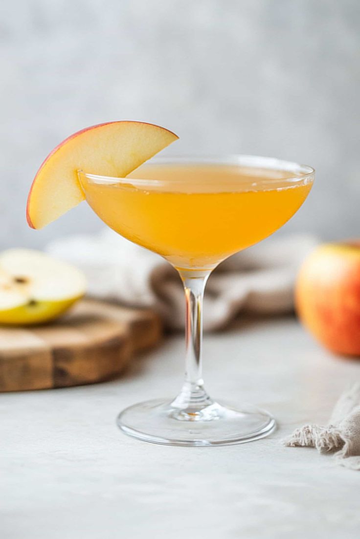 an apple cider sitting on top of a table next to sliced apples