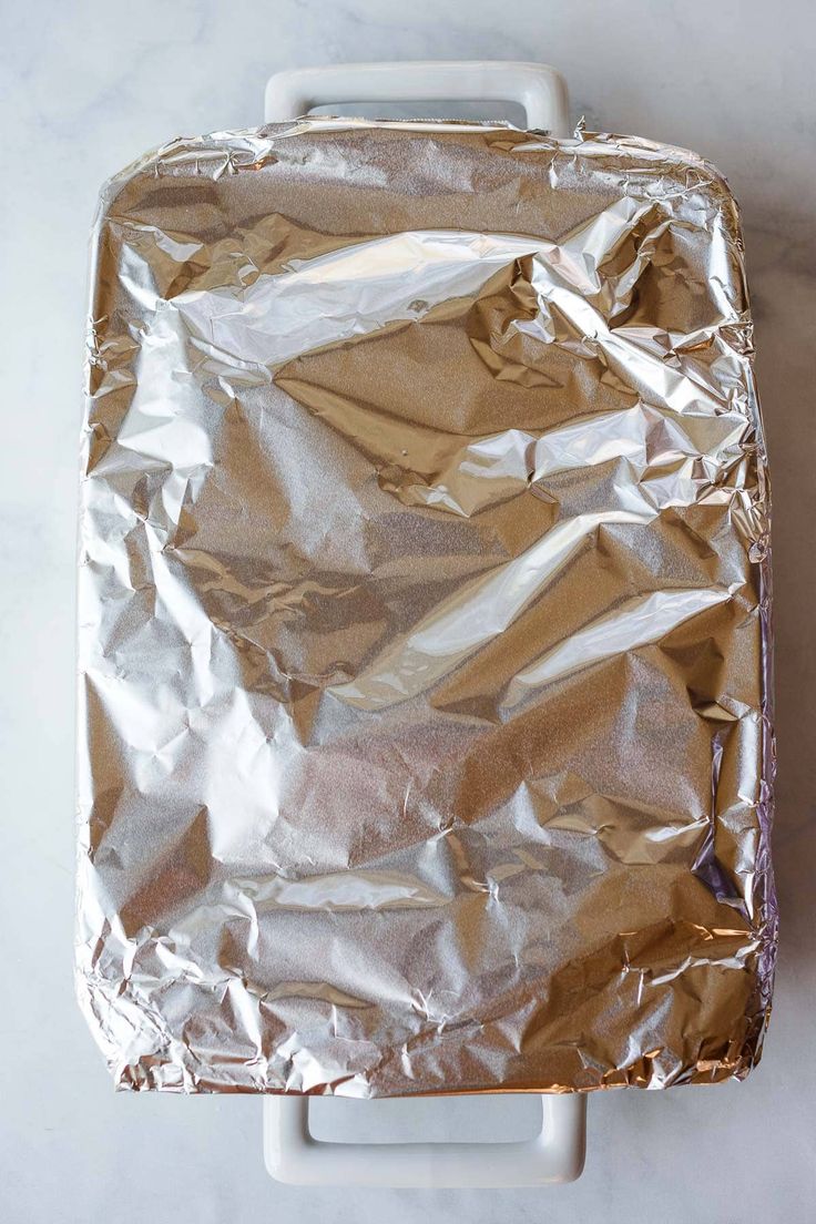 an aluminum foil covered suitcase sitting on top of a white table next to a wall