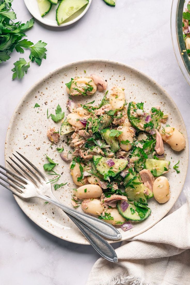 a white plate topped with shrimp and cucumber salad