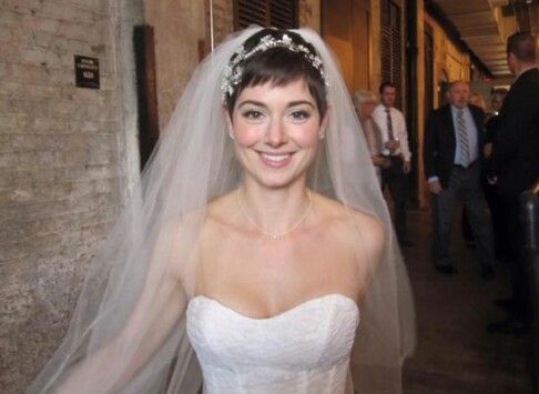 a woman in a wedding dress is smiling at the camera with her veil draped over her head