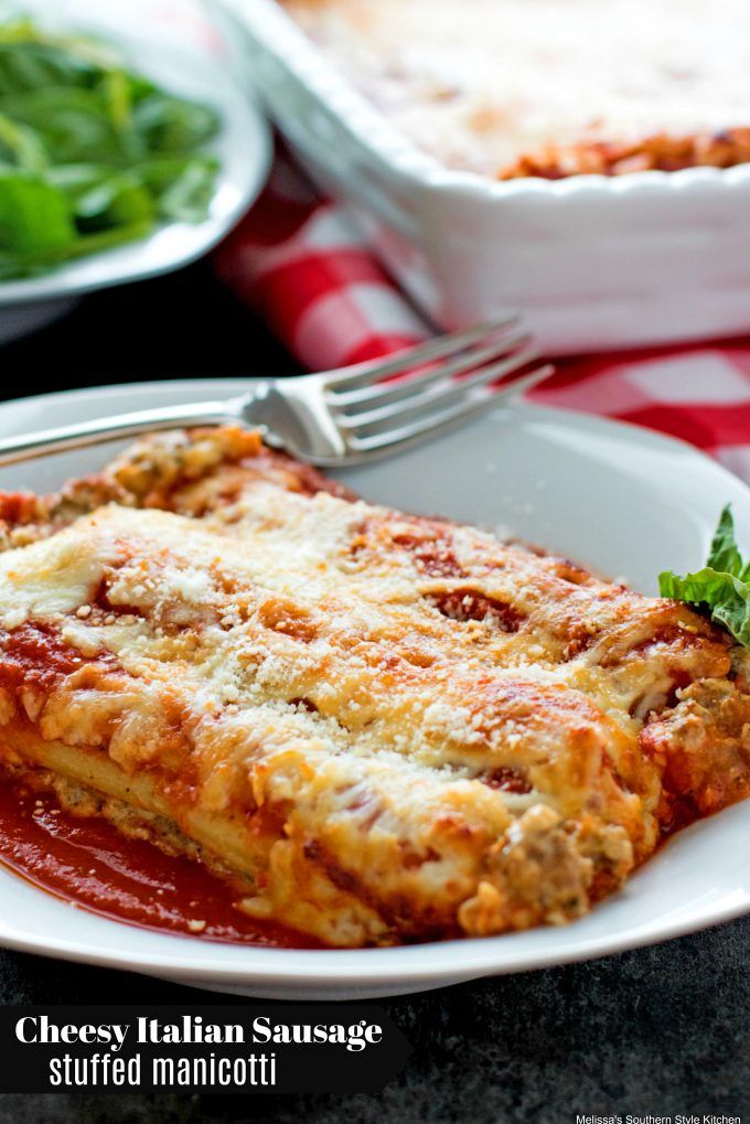 a white plate topped with lasagna covered in sauce next to a green salad