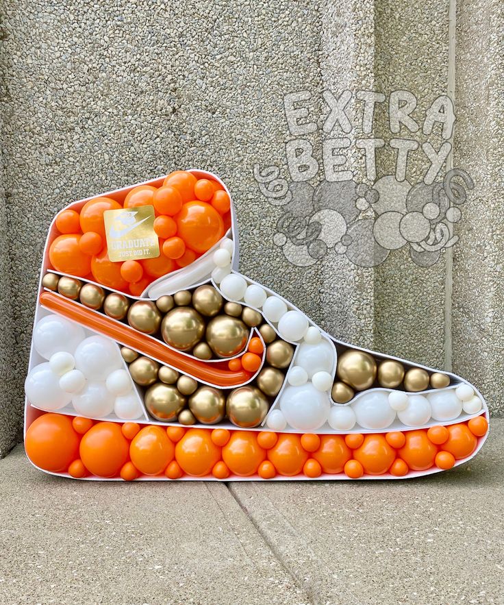 an orange and white nike shoe sculpture on the sidewalk