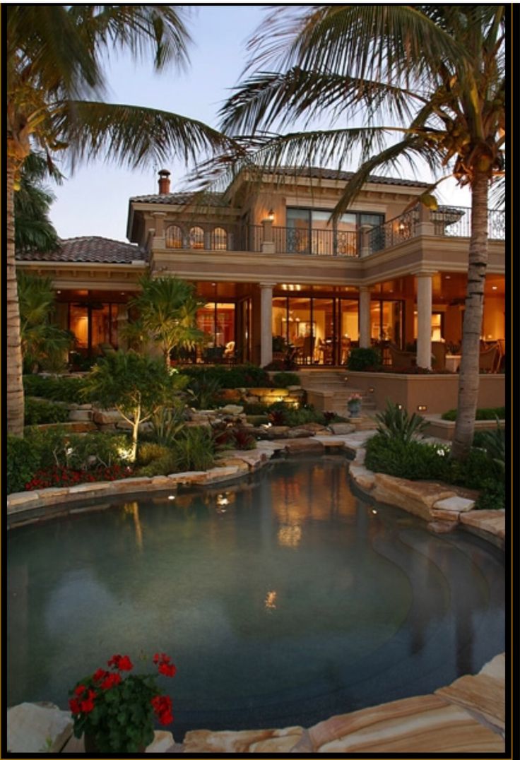 a house with a pool in front of it and palm trees around the pool area