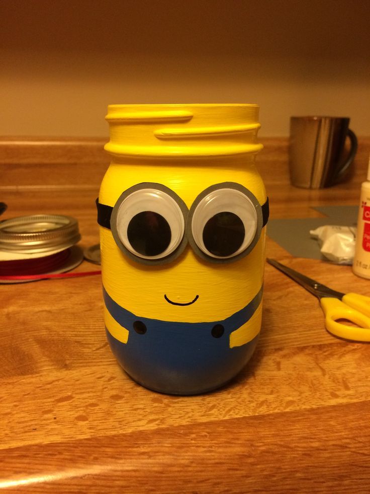 a yellow jar with eyes on it sitting on a table next to scissors and other items