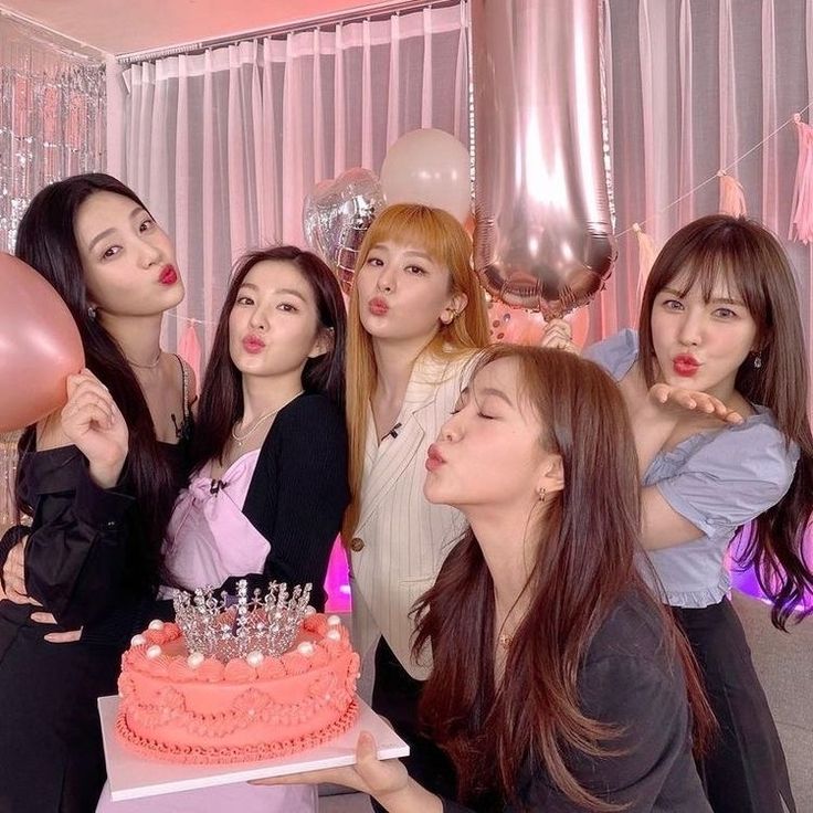 the girls are blowing out their candles on the cake and posing with balloons in front of them