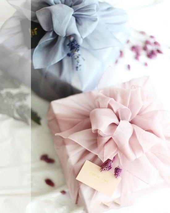 three different types of cakes with tags attached to them on a white tablecloth, one is blue and the other is pink