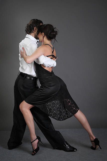 a man and woman are dancing together on a gray background with their arms around each other