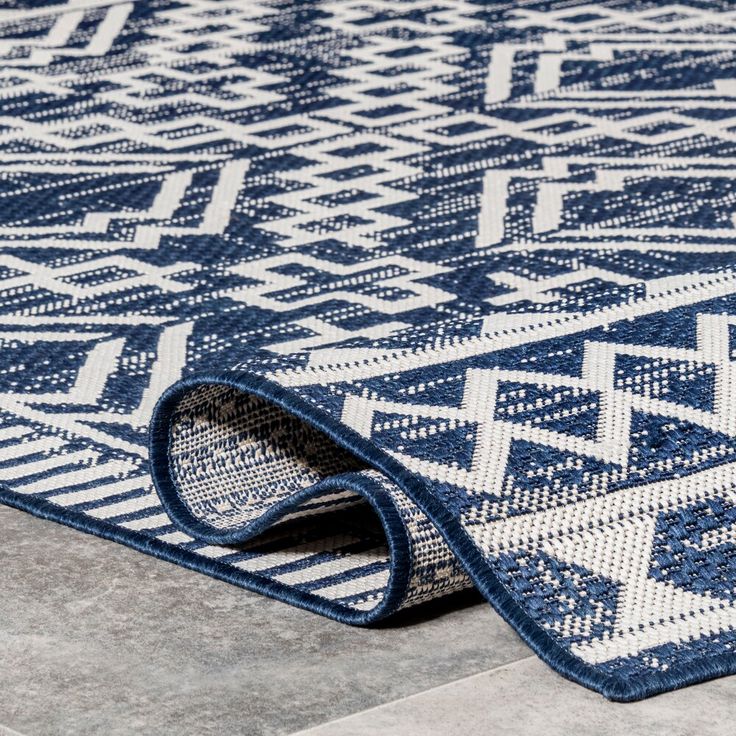 a blue and white rug on the floor with an interesting design in it's center