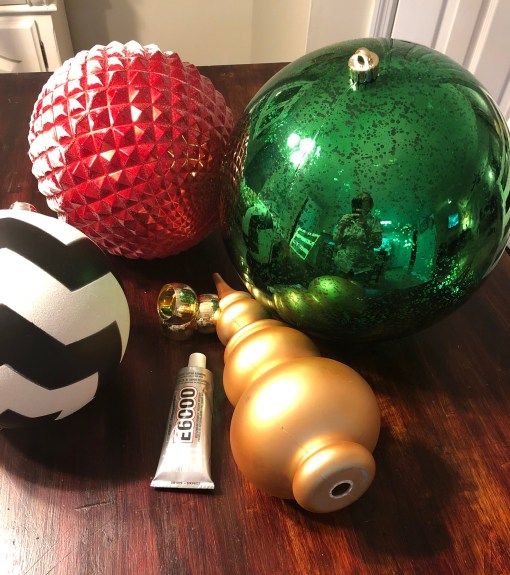 three christmas ornaments on a table with one green ornament and the other gold