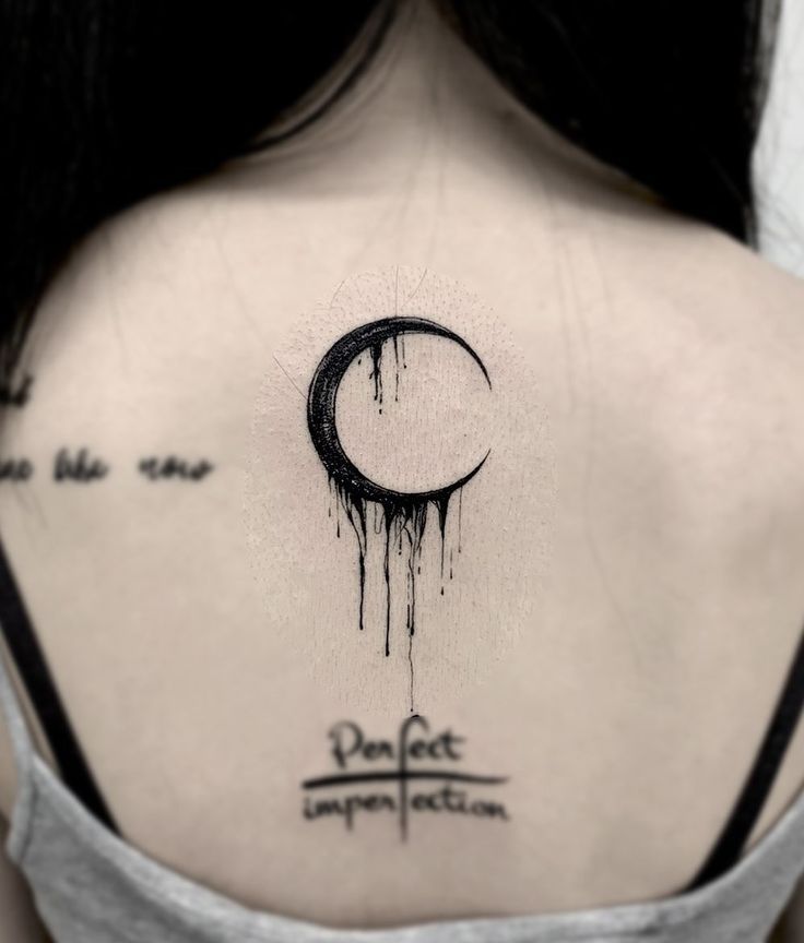 the back of a woman's shoulder with an inked crescent tattoo on it