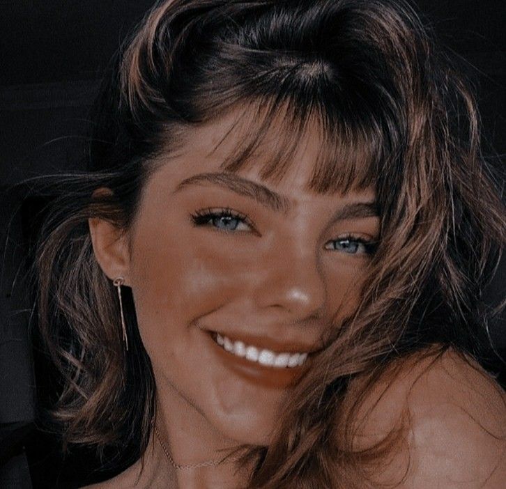 a close up of a woman smiling with her hair blowing in the wind