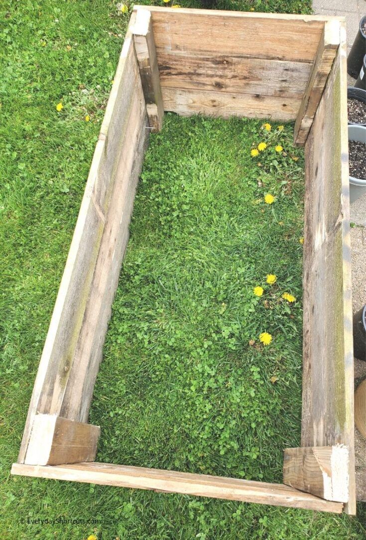 a wooden box sitting in the middle of some grass