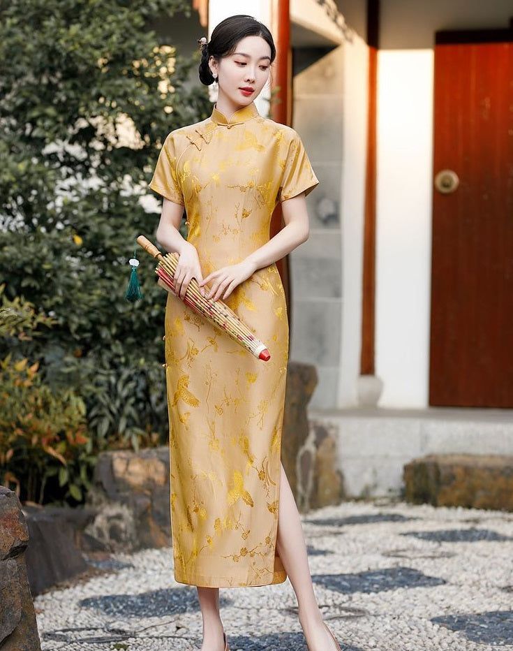 A chinese girl in gold silk qipao  with  intricate floral and bird jacquard patterns with umbrella on hand Elegant Cheongsam With Stand Collar For Festive Season, Elegant Festive Cheongsam With Stand Collar, Formal Elegant Festive Cheongsam, Elegant Festive Formal Cheongsam, Elegant Fitted Cheongsam For Ceremonial Occasions, Elegant Long Cheongsam For Festive Occasions, Elegant Long Ao Dai For Ceremonial Occasions, Elegant Long Ao Dai For Ceremonial Use, Elegant Long Festive Cheongsam