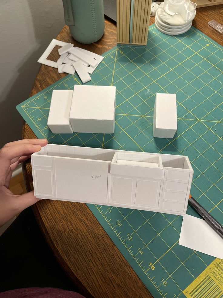 someone is cutting out some white boxes on a table