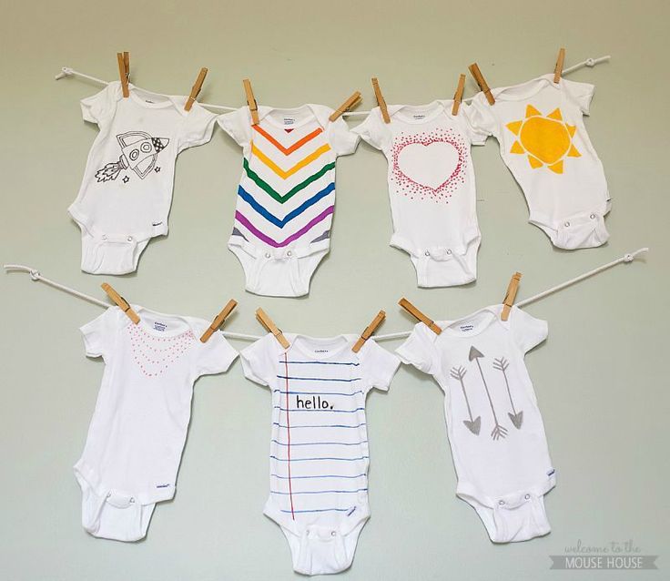 baby onesuits hanging on clothes pins with the word hello written on them in different colors