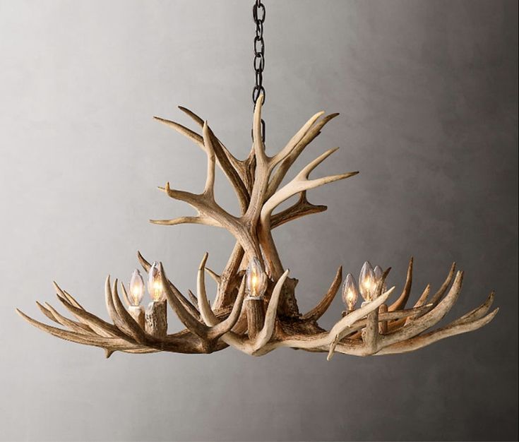 a chandelier made out of antlers hanging from a chain on a gray wall