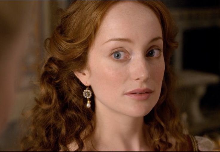 a close up of a person wearing earring's and looking at the camera