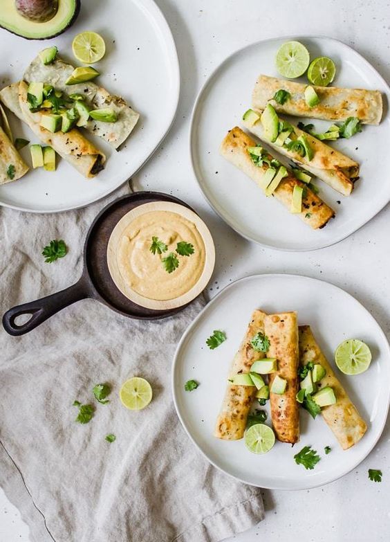 three plates with food on them sitting next to an avocado and lime wedges