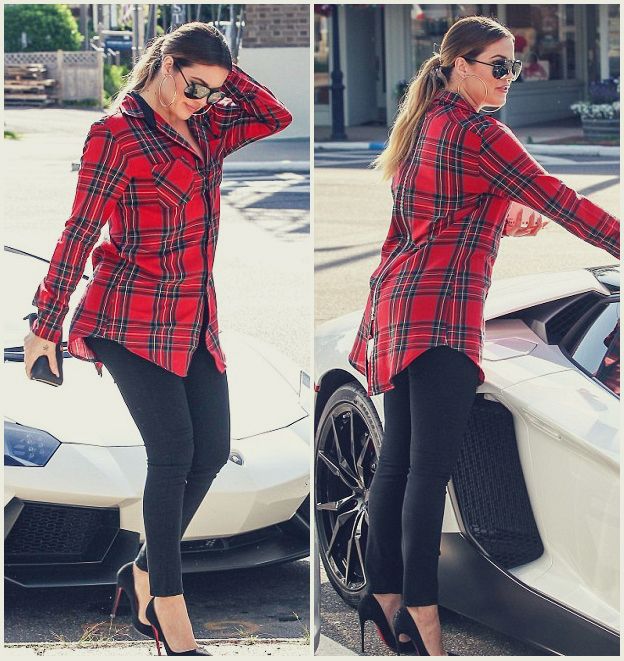 a woman standing next to a white car wearing black pants and red plaid shirt with high heels