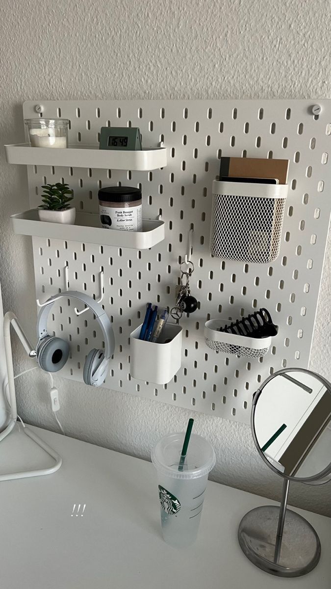 a white desk topped with a computer monitor next to a cup