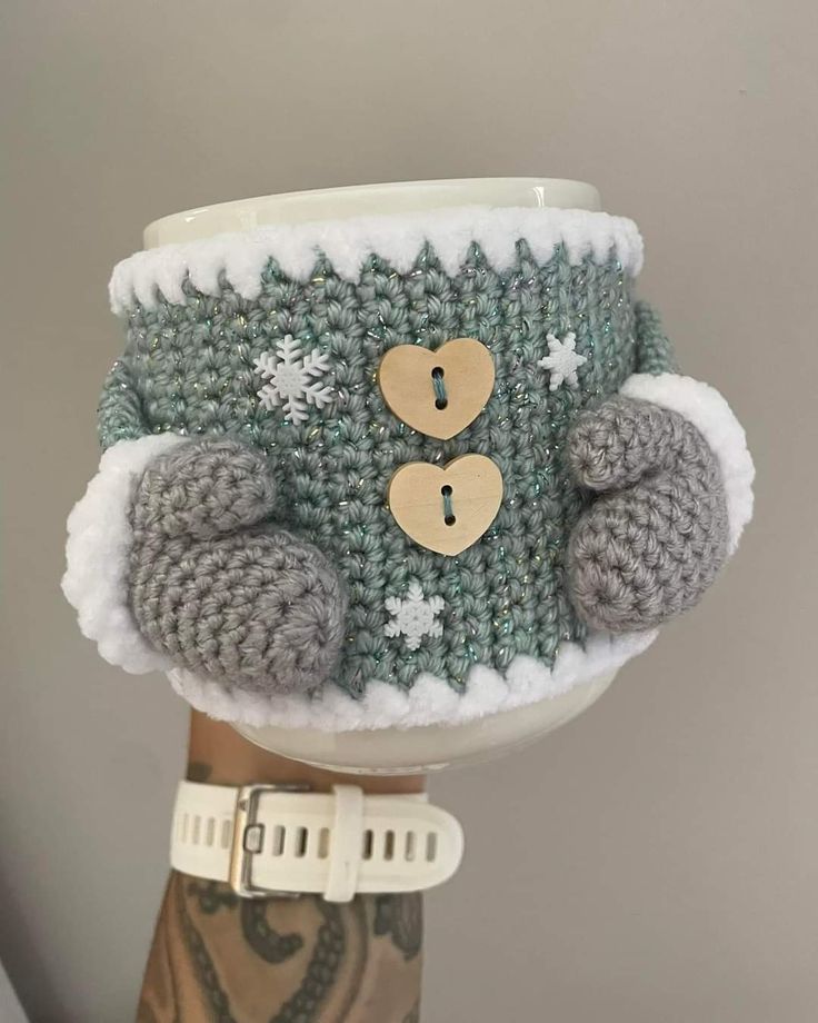 a knitted cup cozys up with buttons and snowflakes on the inside