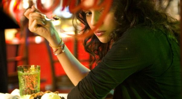 a woman sitting at a table with food in front of her and eating from a fork