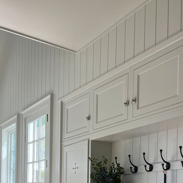 a kitchen with white cabinets and hooks on the wall