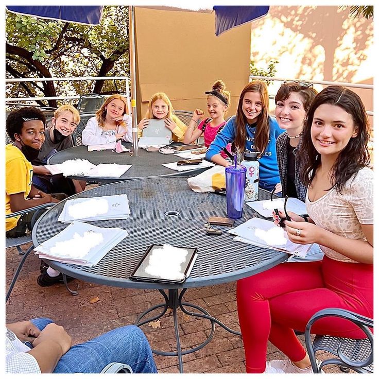 a group of people sitting around a table with notebooks and pens in their hands