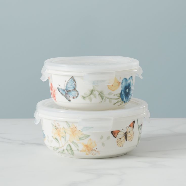 two bowls with butterflies painted on them sitting on a marble countertop next to each other