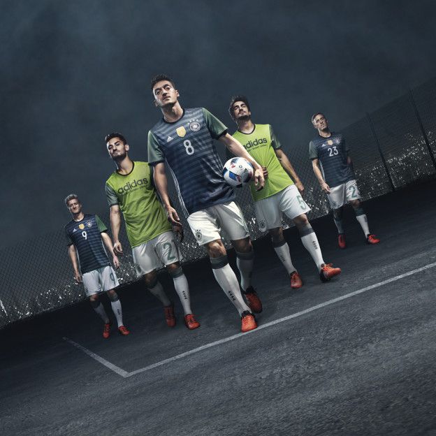 a group of soccer players in green and blue uniforms are walking on the field with a ball