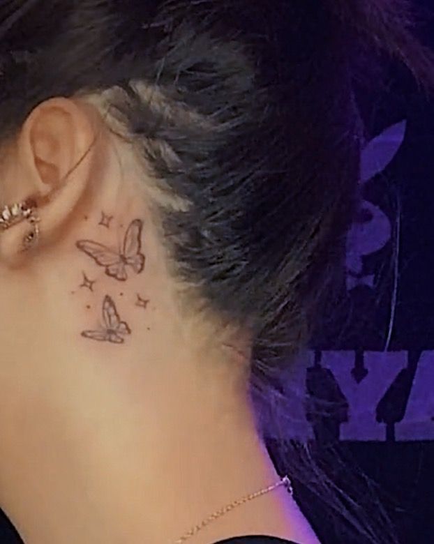 a woman's behind the ear tattoo with butterflies and stars on her left side