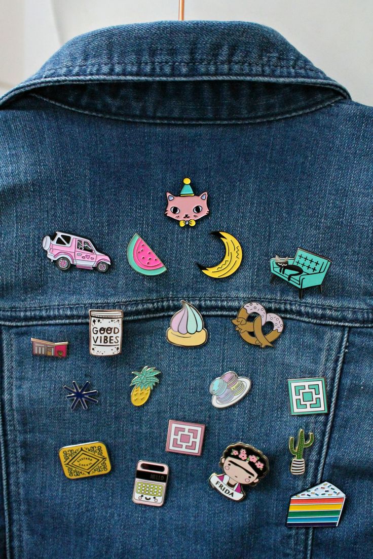 the back of a denim jacket with various pins and magnets on it, all in different shapes and sizes