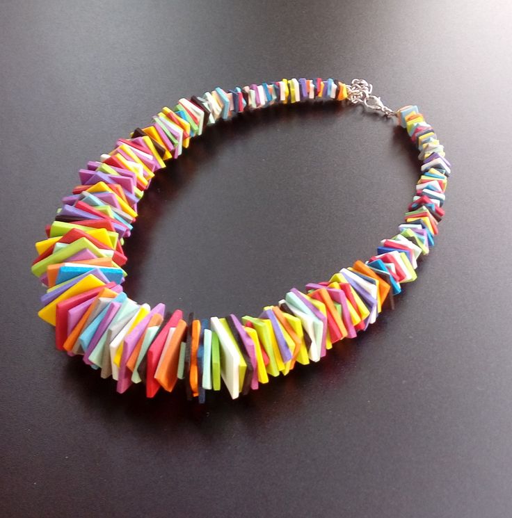 a multicolored necklace is displayed on a black surface with a silver chain and clasp