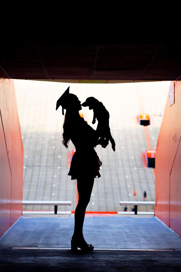 a woman holding a baby in her arms while standing under an overpass at a football stadium