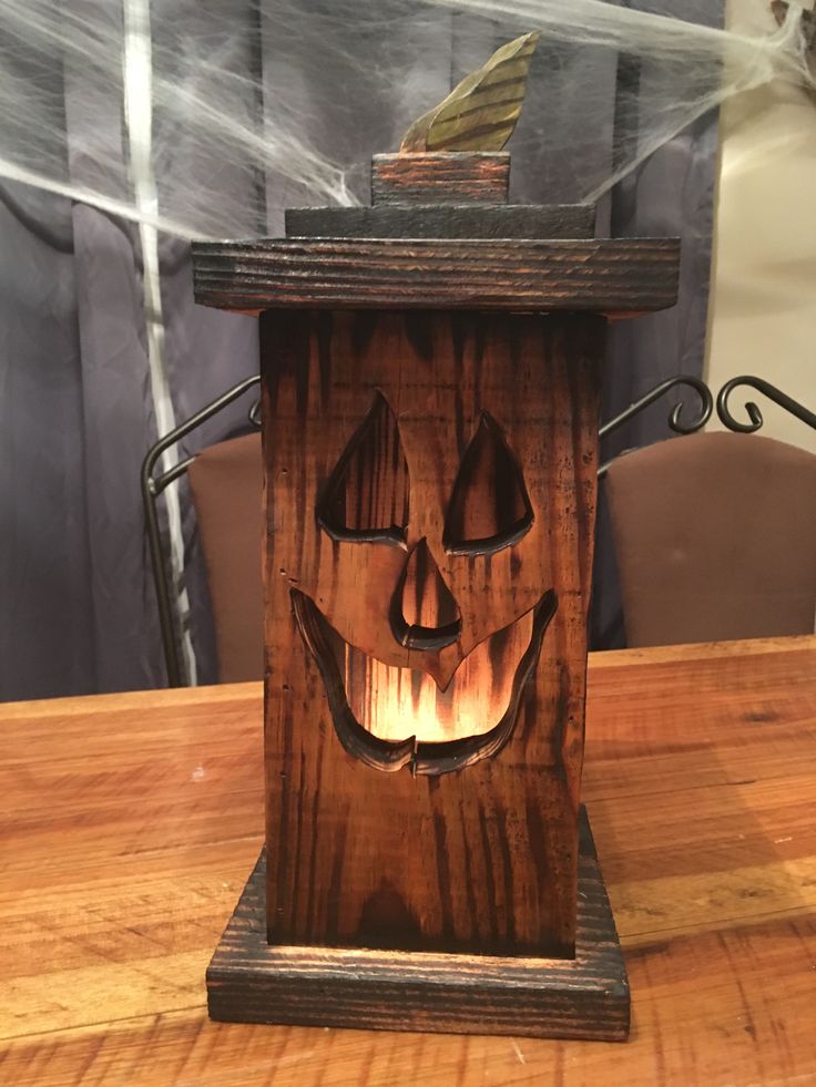 a wooden clock with a carved pumpkin face on it's front and sides, sitting on top of a table