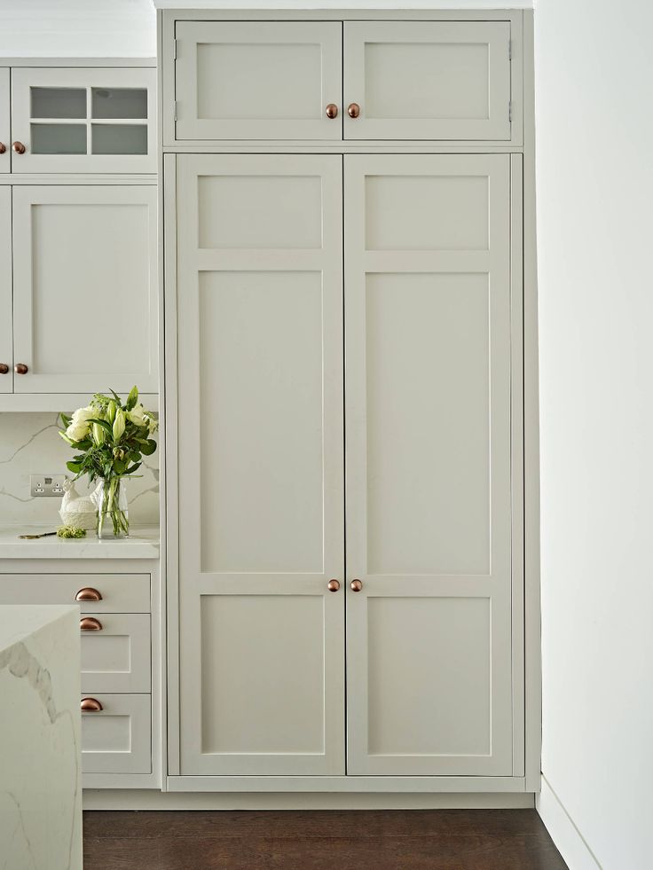 a kitchen with white cabinets and marble counter tops