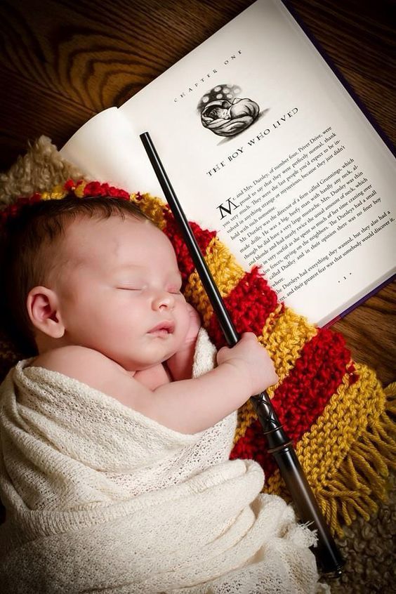 a baby is sleeping next to an open harry potter book with a wand in it