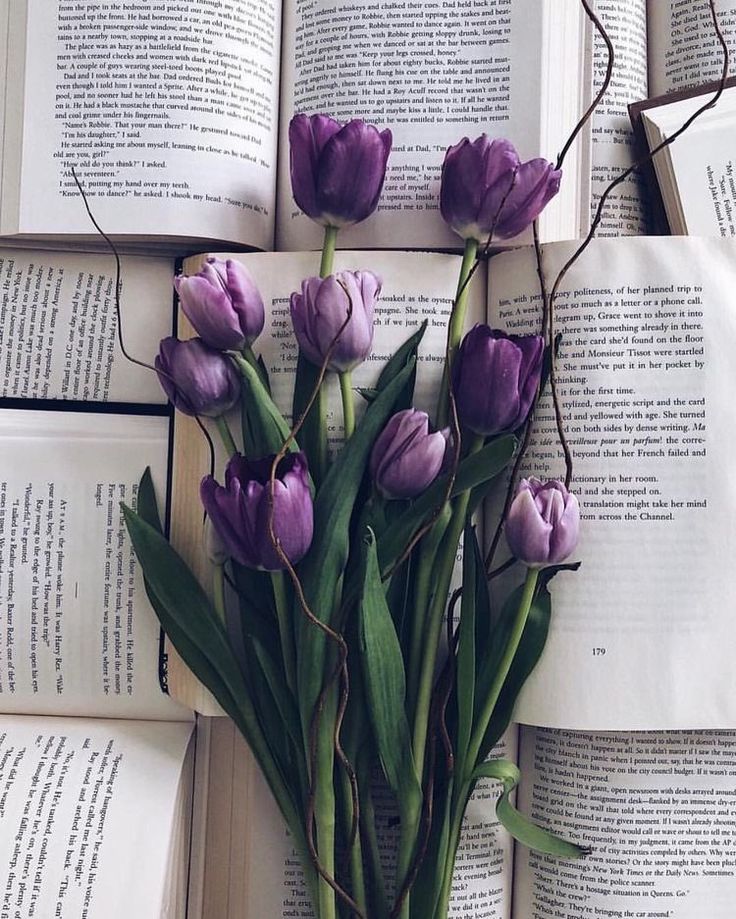 there are many books stacked on top of each other with purple flowers in the middle