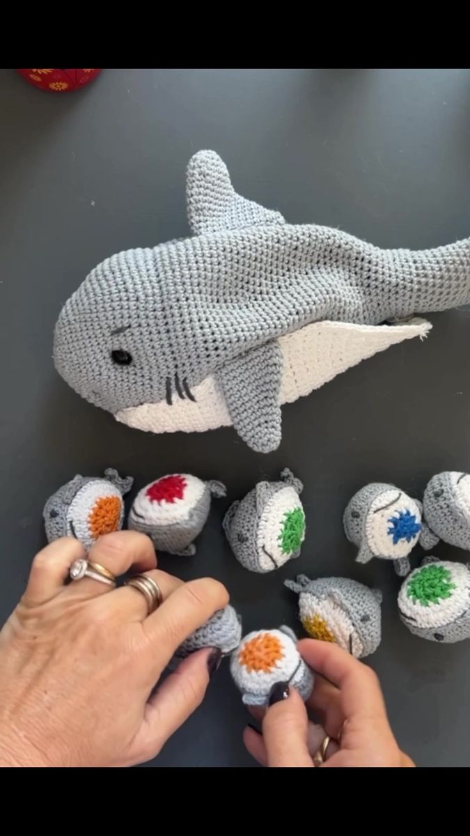 someone is making knitted toys out of yarns and fabric, including a stuffed shark