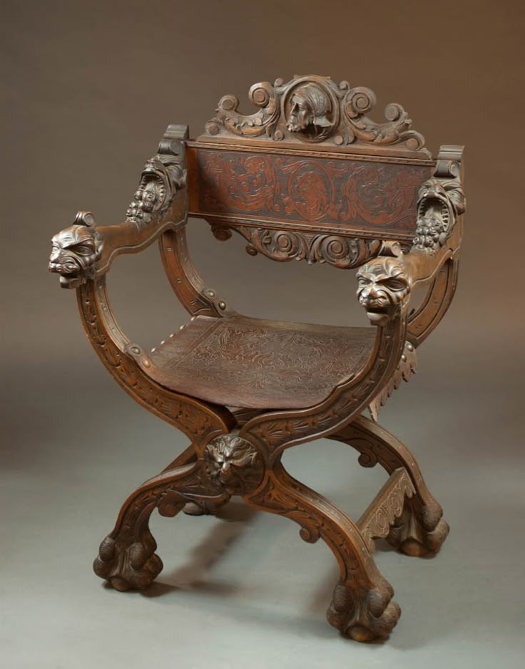 an old wooden chair with carvings on the armrests and foot rests against a gray background