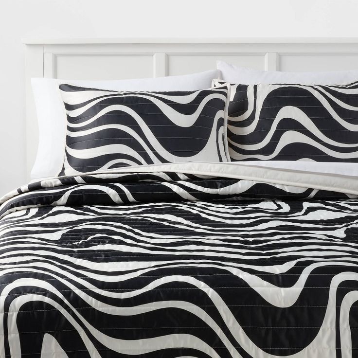 a black and white bed with zebra print on it's comforter, pillows and pillow cases