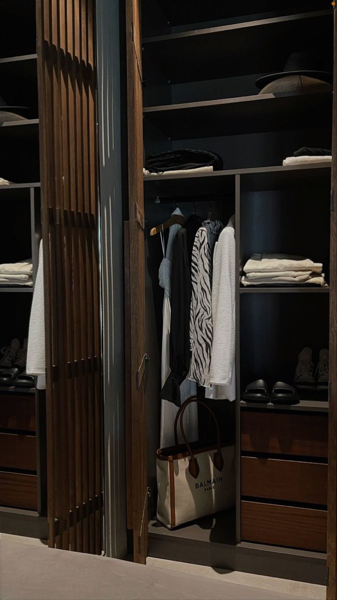 an open closet with clothes and handbags in it