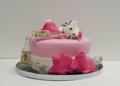 a cake with pink frosting and decorations on it, including a cat sitting on top of the cake