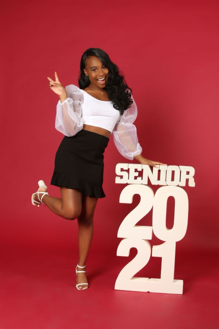 a woman posing in front of a sign that says senior 20 - 21 and has her hand up