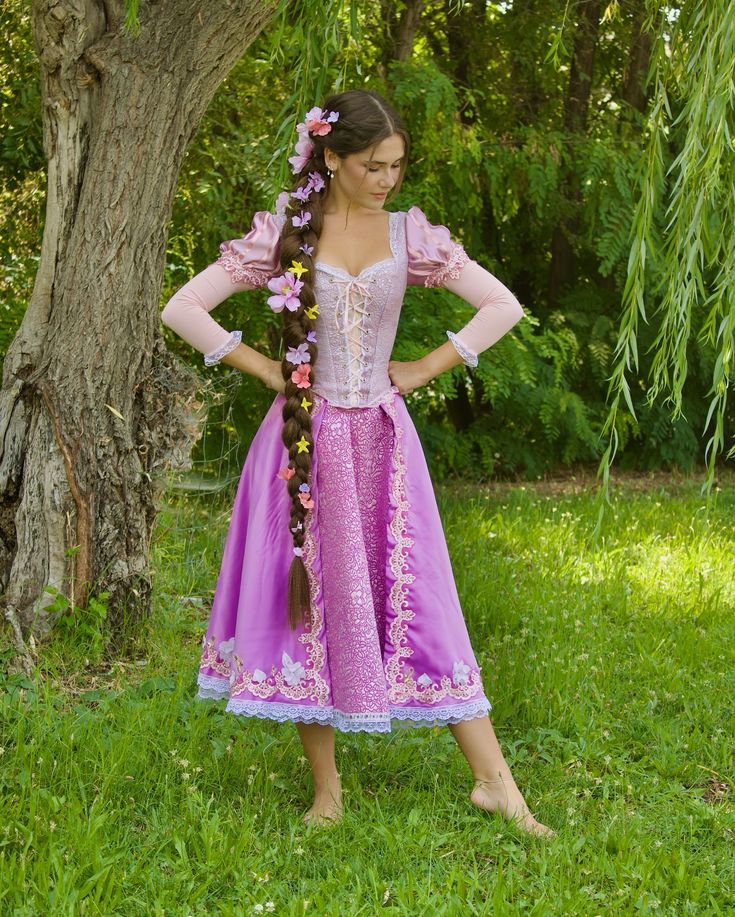 a woman wearing a purple dress standing in front of a tree