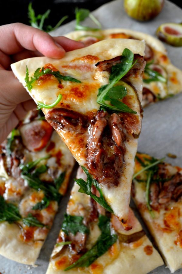 a person holding up a slice of pizza with meat and veggies on it