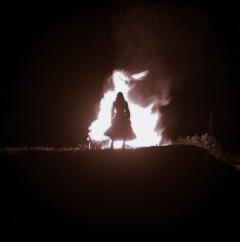 a woman standing in front of a fire