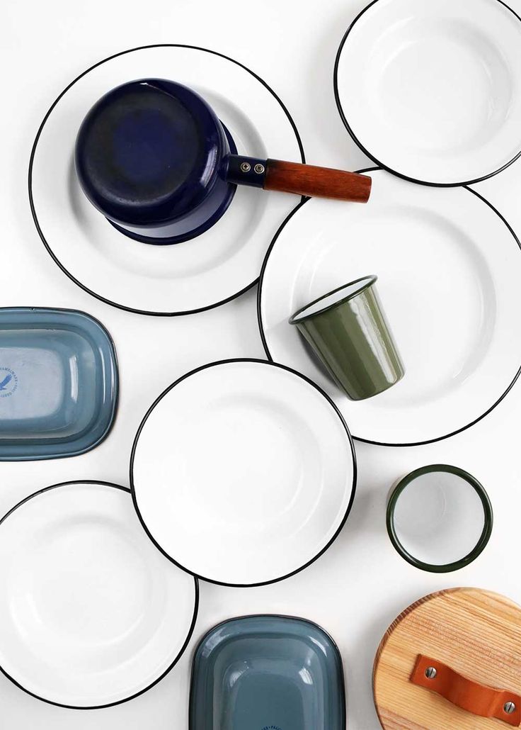 several plates and bowls are arranged on a white surface with a wooden spatula in the middle